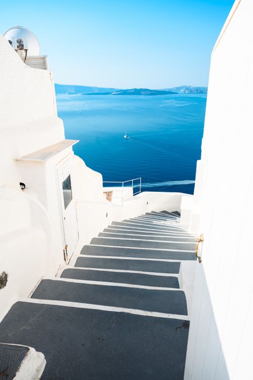Free A picturesque view of whitewashed steps in Santorini leading to a serene Aegean Sea. Stock Photo