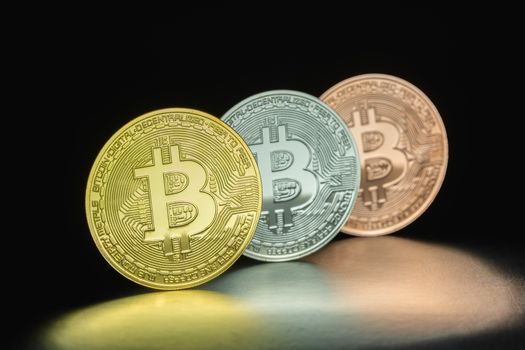 Close-up of three Bitcoin coins in dramatic lighting, symbolizing cryptocurrency investment and fintech innovation.
