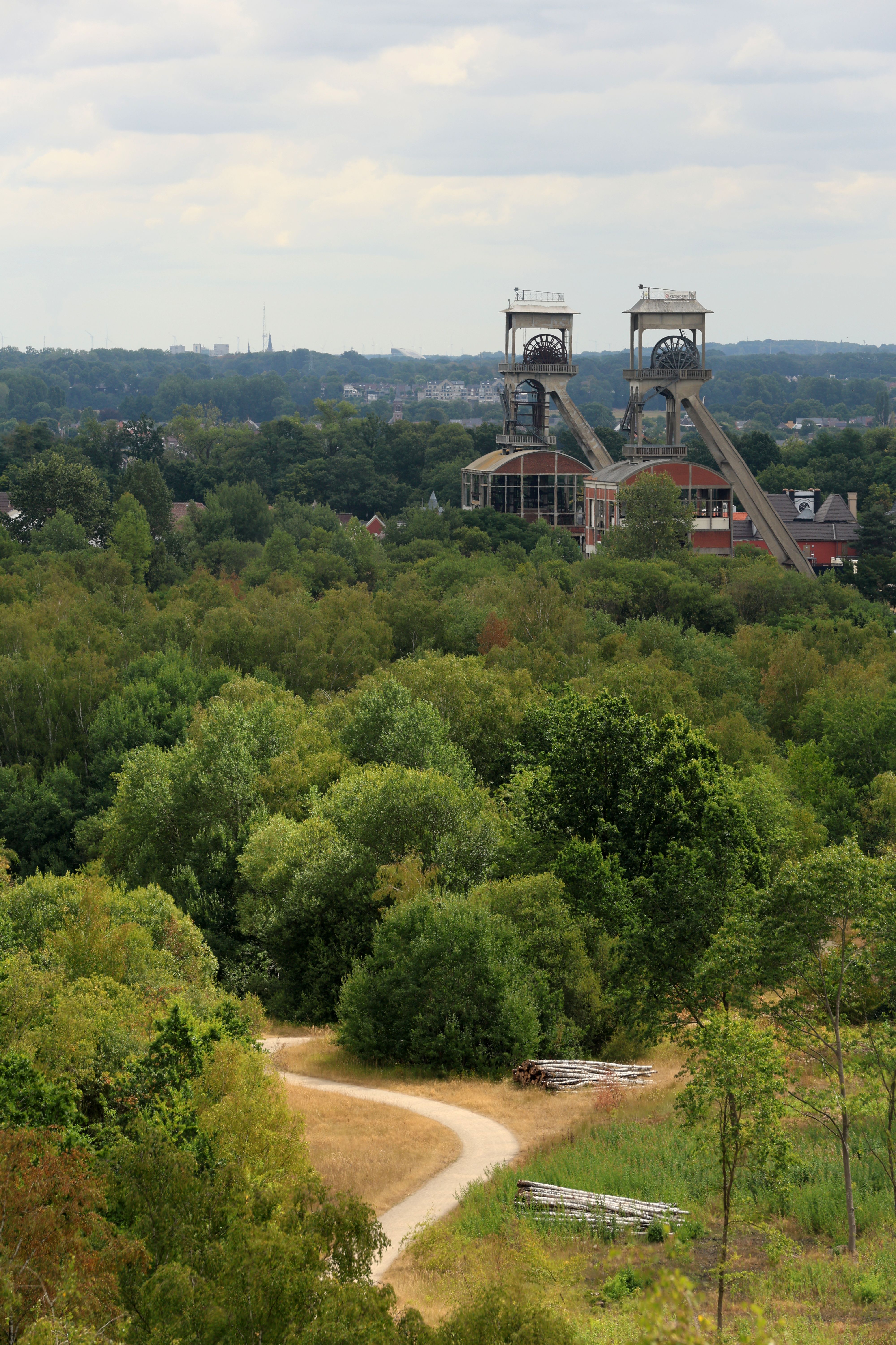 Scenic aerial view of lush greenery and old mining structures in Maasmechelen, showcasing nature's beauty amidst industrial history.