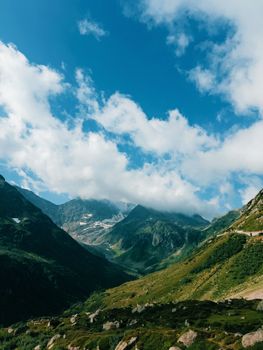 Breathtaking view of a lush alpine valley with a clear blue sky and majestic mountains.