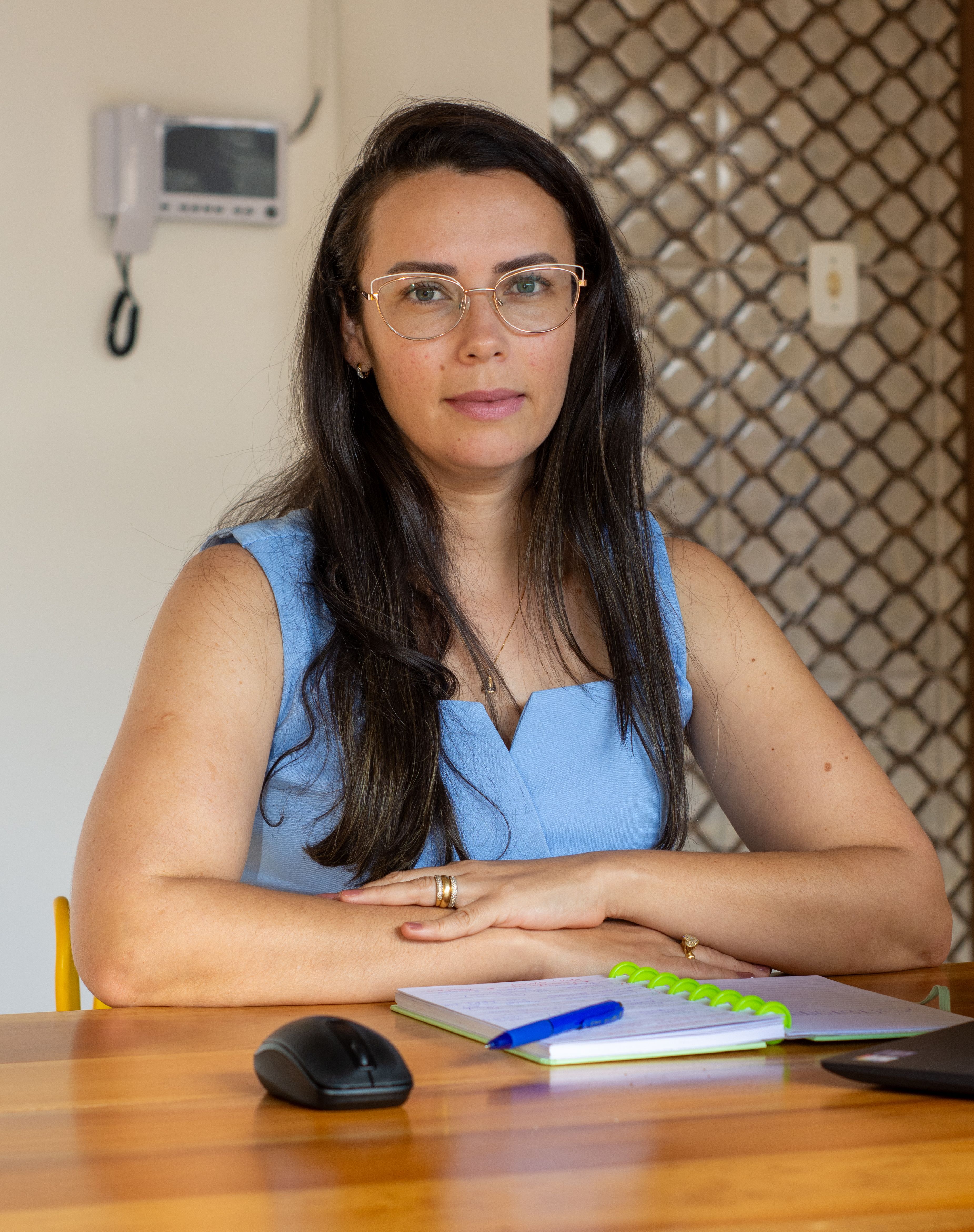 Confident woman seated at a desk with notebook and computer accessories, demonstrating productivity and focus.