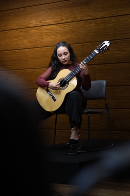 Free A female musician passionately plays a classical guitar on stage indoors. Stock Photo