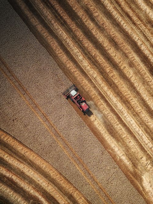 Free Drone captures a tractor harvesting fields in rural England, showcasing agricultural patterns. Stock Photo
