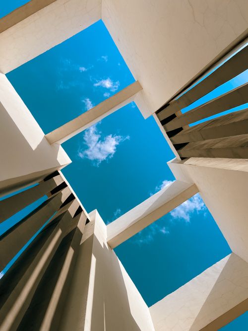Free Looking up through architectural structures to a bright blue sky. Stock Photo
