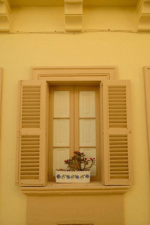 Free A beautiful Maltese window with a shuttered design and flower box, showcasing Mediterranean architecture. Stock Photo