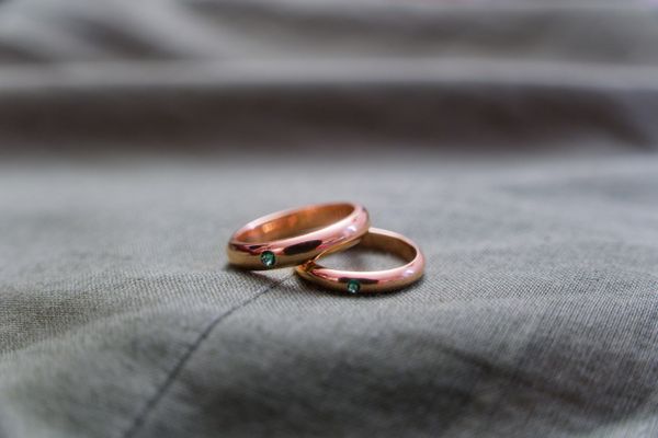Alliances en or rose ornées d'émeraudes sur un tissu gris