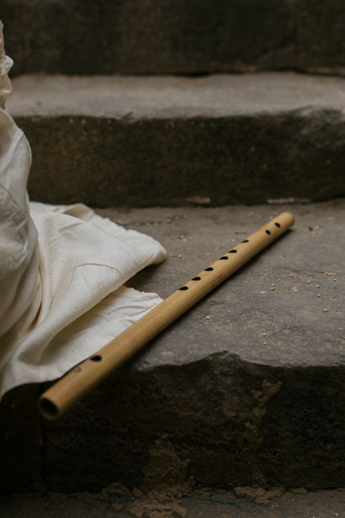 Free A wooden flute resting on rustic stone steps with cloth draped beside. Stock Photo