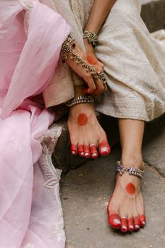 Close-up of beautifully adorned feet with traditional henna and anklets, wearing bridal attire.