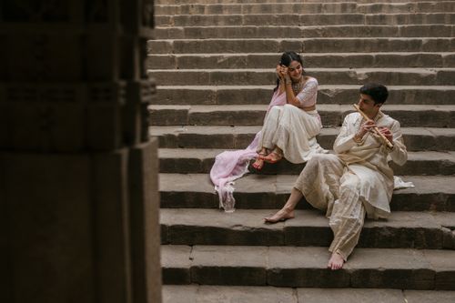 Free A couple in traditional Indian attire sitting on ancient stone steps, exuding a serene ambiance. Stock Photo