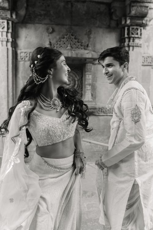 Free Black and white image of a joyful Indian couple in traditional attire celebrating amid ancient architecture. Stock Photo