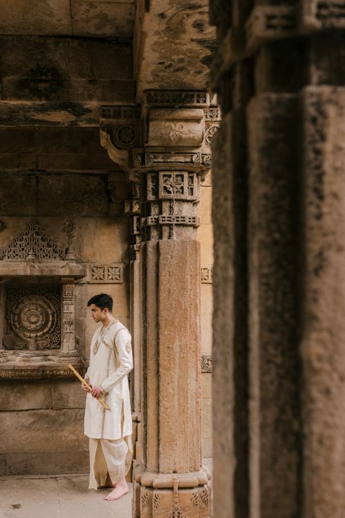 Free Man in traditional attire holding a flute at an ancient architectural site. Stock Photo