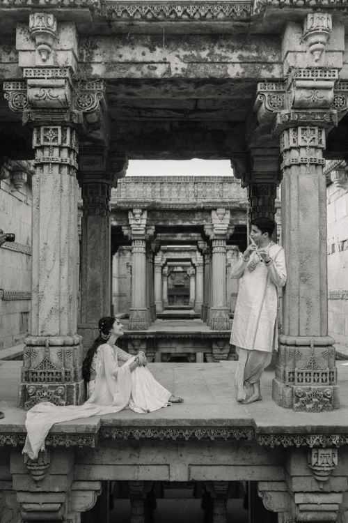 Free A couple dressed in traditional attire in a historic stepwell scene, artistic mood. Stock Photo