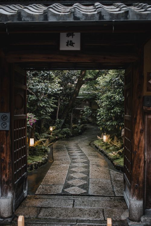 Free Serene pathway through a traditional Japanese garden, framed by a wooden entrance in Kyoto, Japan. Stock Photo