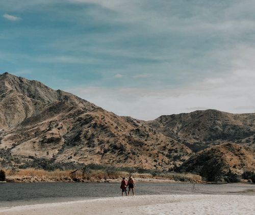 Free A couple hiking in a beautiful mountainous landscape under a clear blue sky. Stock Photo