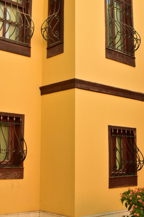 Free Detailed view of a yellow building corner with ornate wrought iron windows. Stock Photo