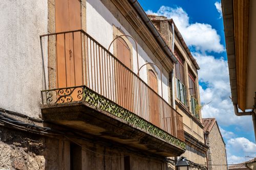 Free Traditional village facade featuring an ornate wooden balcony under a bright blue sky. Stock Photo