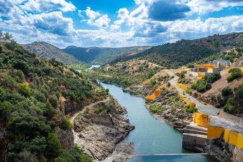 Free Aerial view of a river flowing through mountains with a hydroelectric dam Stock Photo