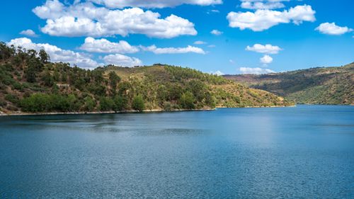 Free Tranquil mountain lake with lush greenery and clear blue skies reflecting on the water. Stock Photo