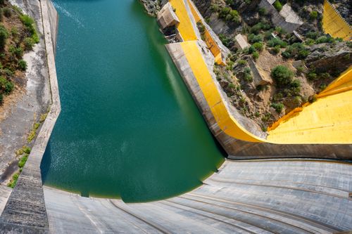 Free Stunning downward view of a massive hydroelectric dam with vibrant water and concrete structures. Stock Photo