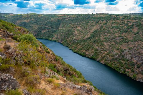 Free Breathtaking view of a river gorge with lush green cliffs and dramatic clouds in the sky. Stock Photo