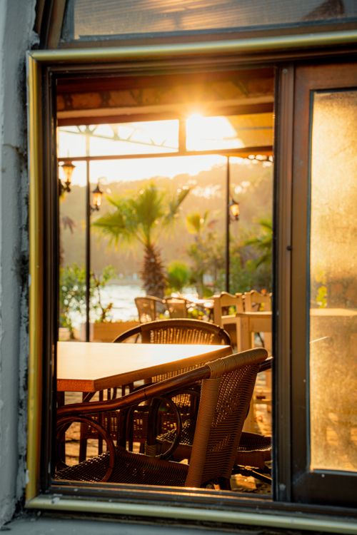 Free Warm evening sunlight fills a charming outdoor cafe by the water. Stock Photo