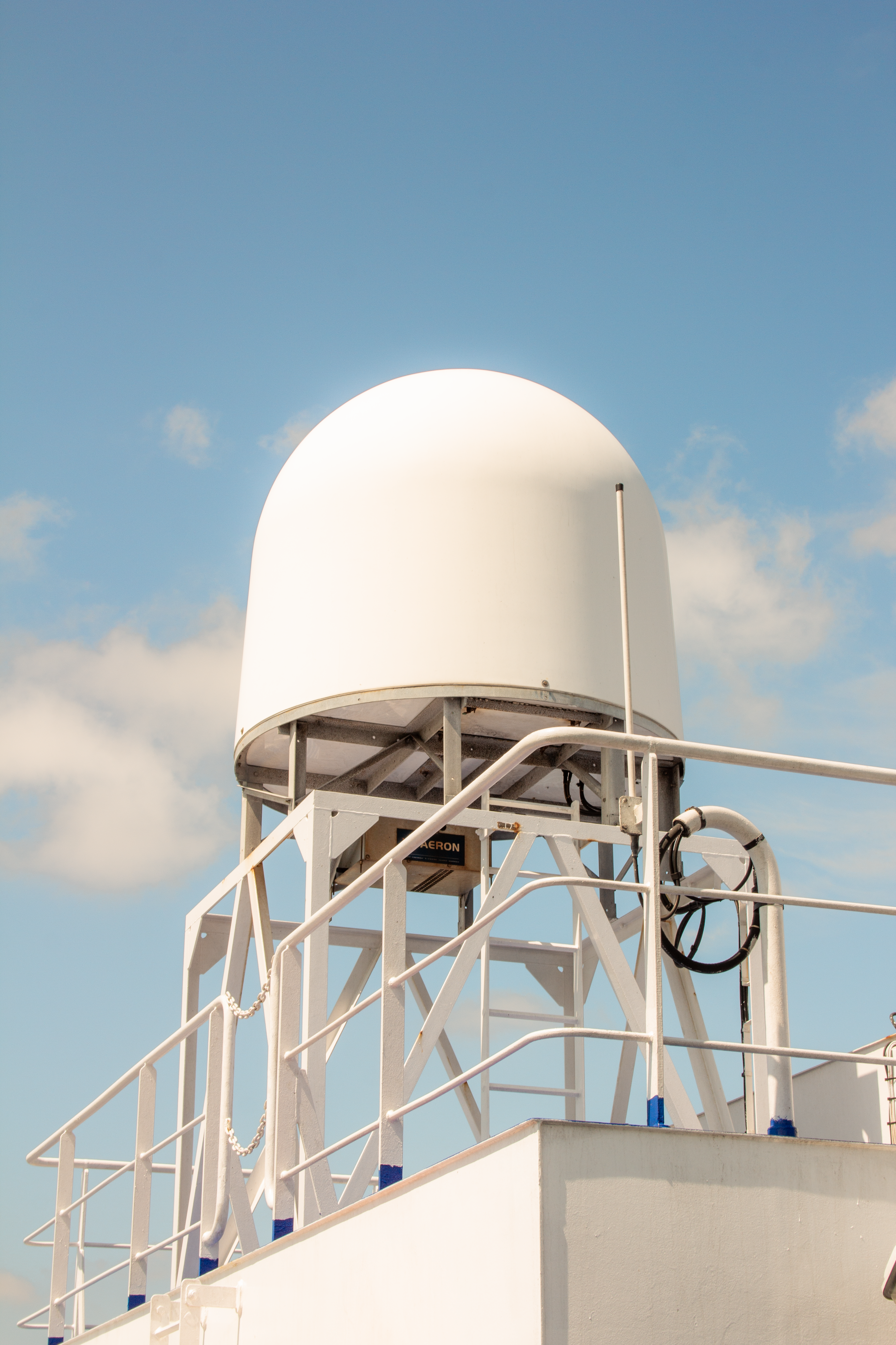 Marine radar on a boat against a clear blue sky, showcasing modern technology.
