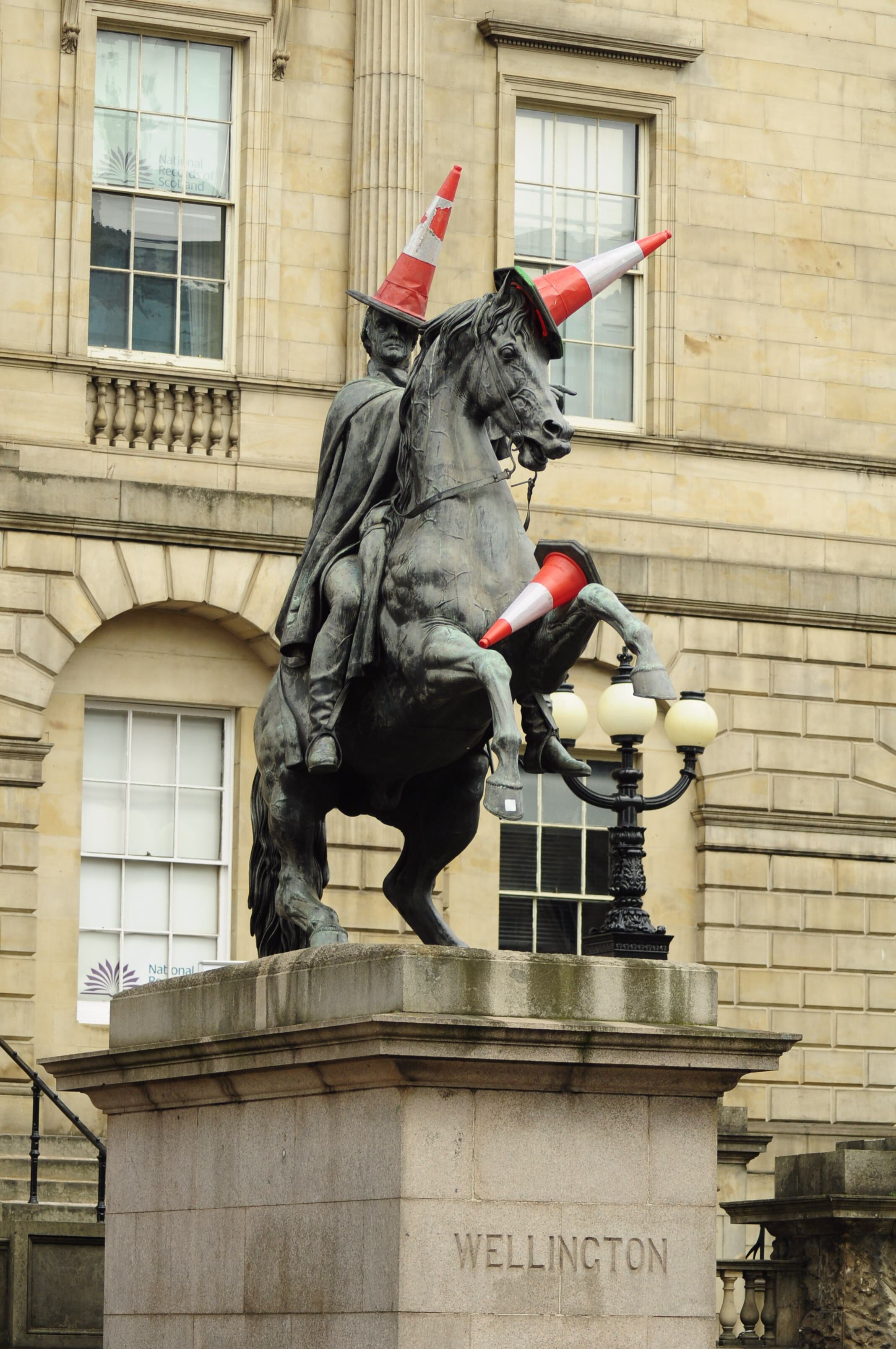 Statue of Duke of Wellington in Edinburgh humorously adorned with traffic cones.