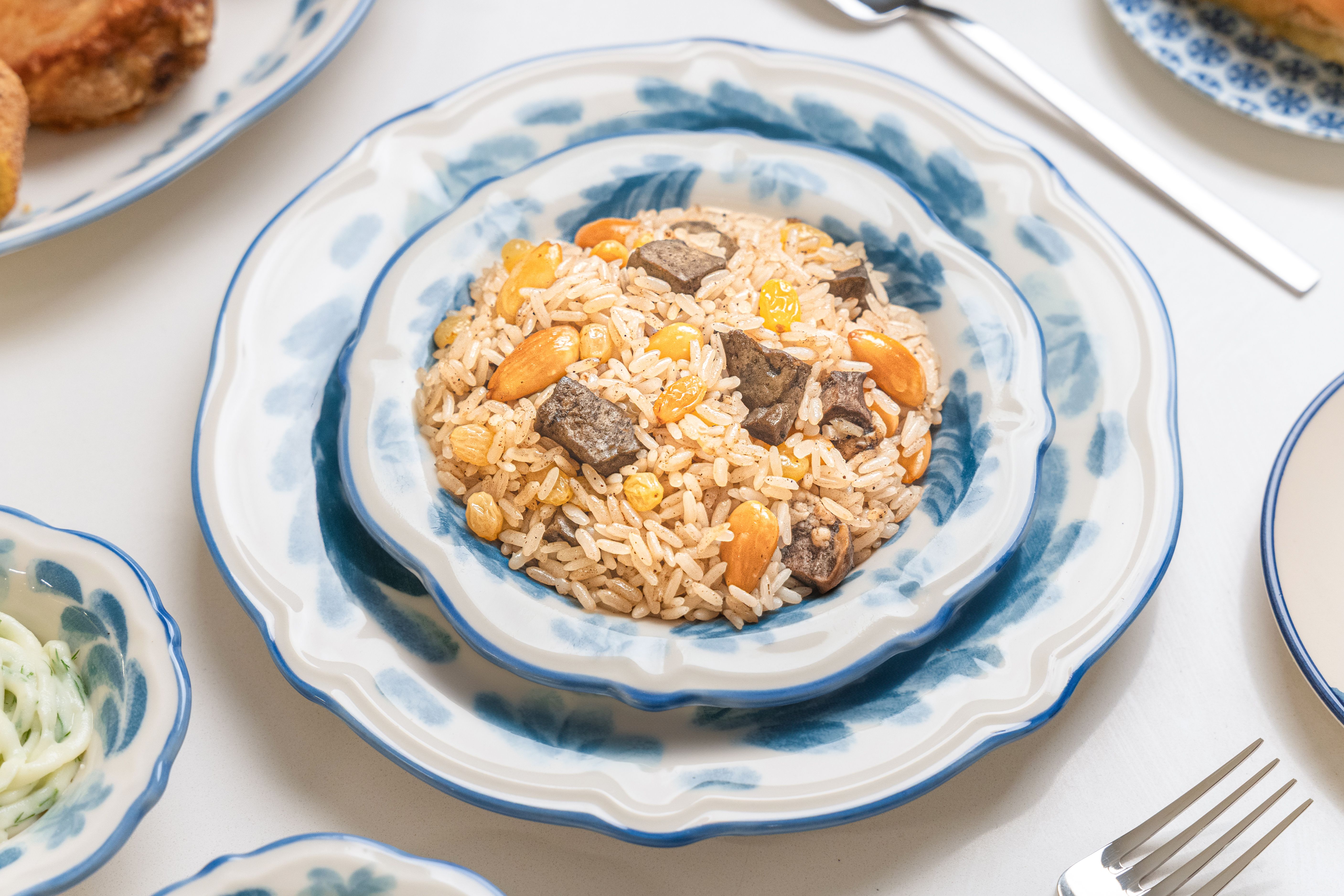 Appetizing rice with almonds, corn, and beef served elegantly on a blue patterned plate.