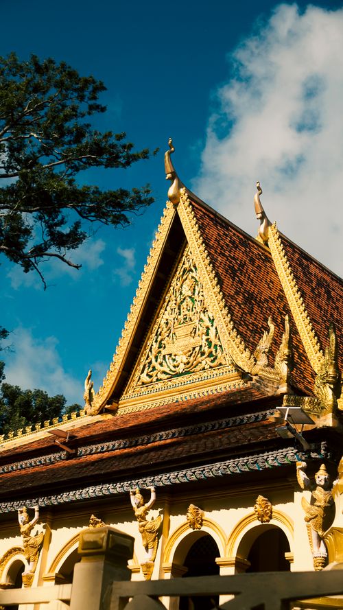 Free Stunning temple facade with intricate carvings in Nguyệt Hóa, Vĩnh Long, under a clear blue sky. Stock Photo