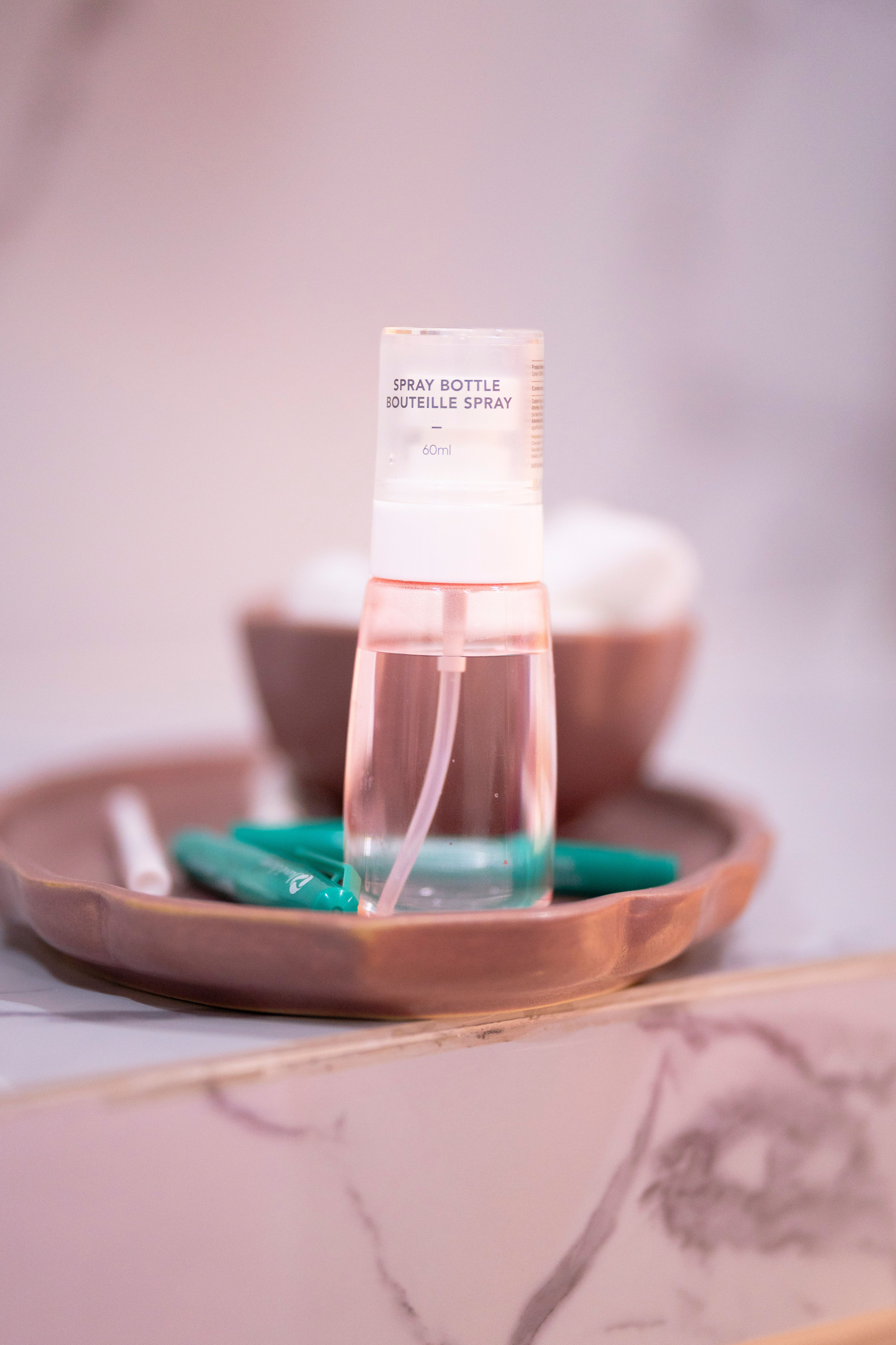 Elegant spray bottle on a ceramic tray in a minimalist bathroom setting with soft lighting.