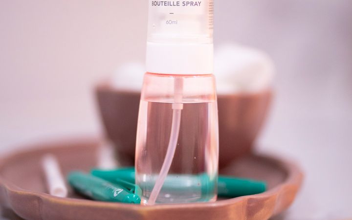 Elegant spray bottle on a ceramic tray in a minimalist bathroom setting with soft lighting.