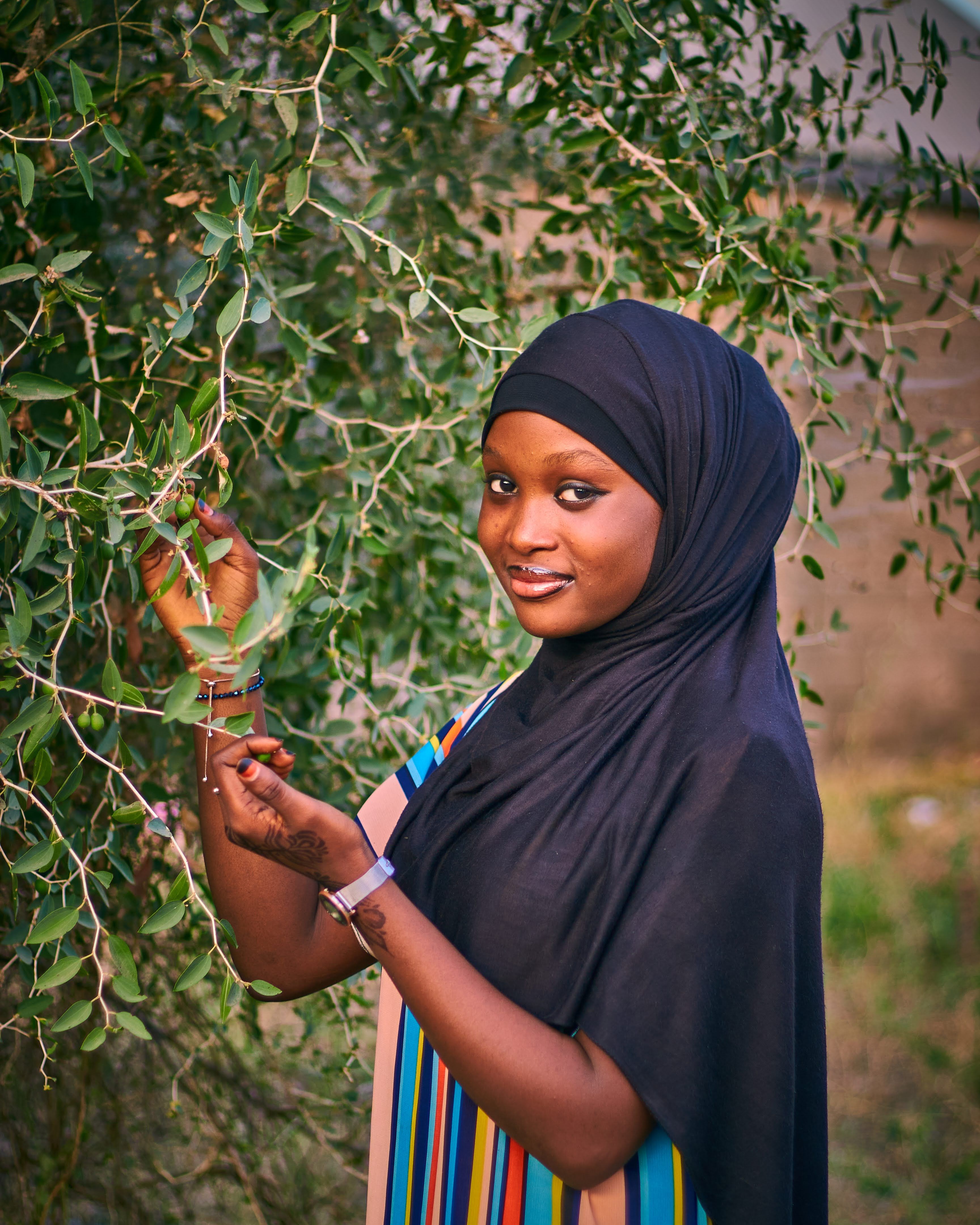 Elegant portrait of a woman in traditional attire amidst lush greenery in Abuja, Nigeria.
