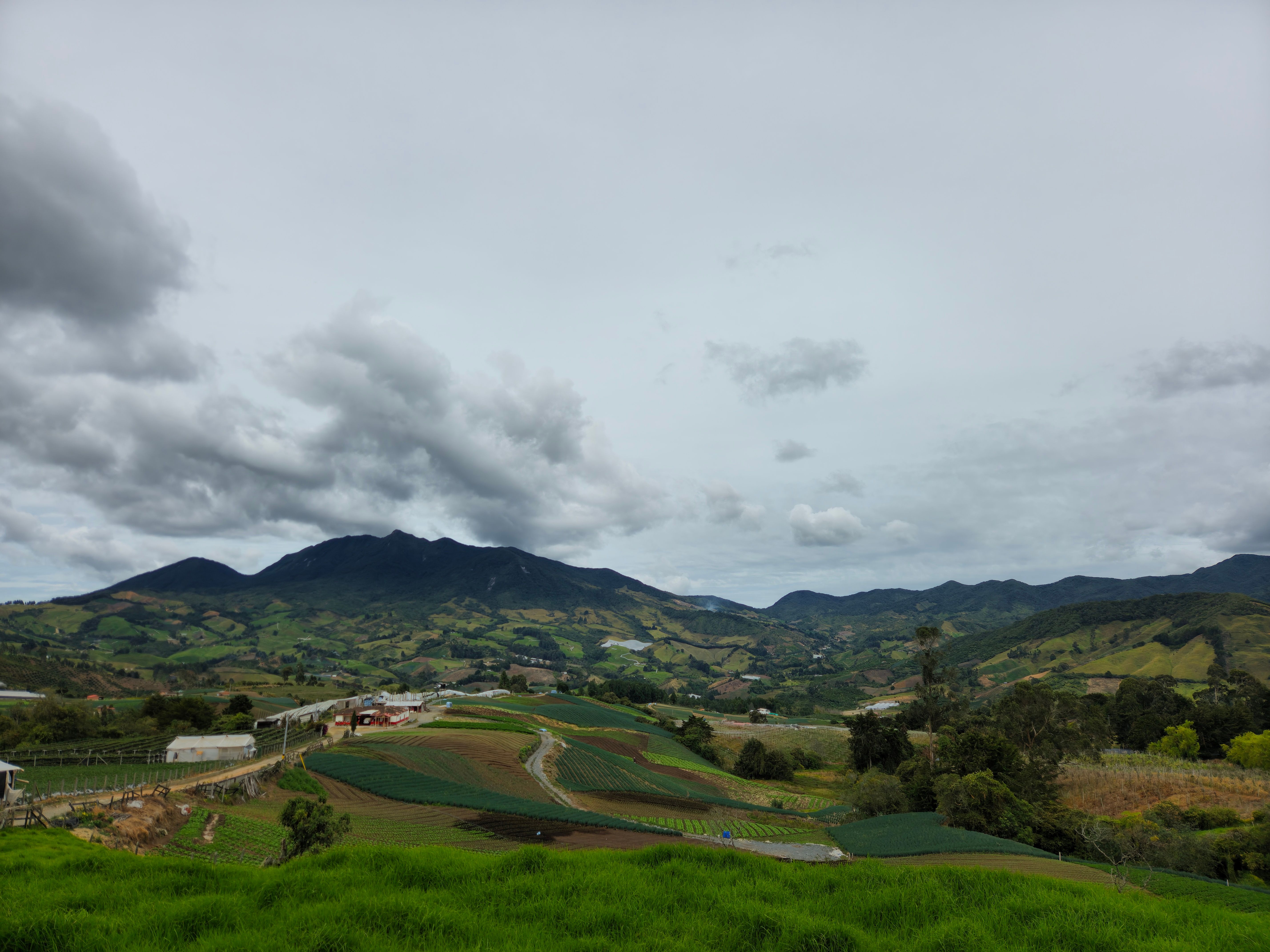 Panoramic landscape of Sonsón, Antioquia showcasing lush green fields under a cloudy sky.