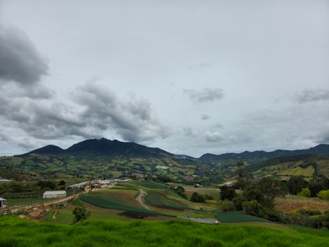 Panoramic landscape of Sonsón, Antioquia showcasing lush green fields under a cloudy sky.