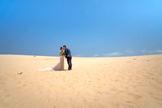 一对优雅的情侣在蓝天下的沙漠中浪漫接吻