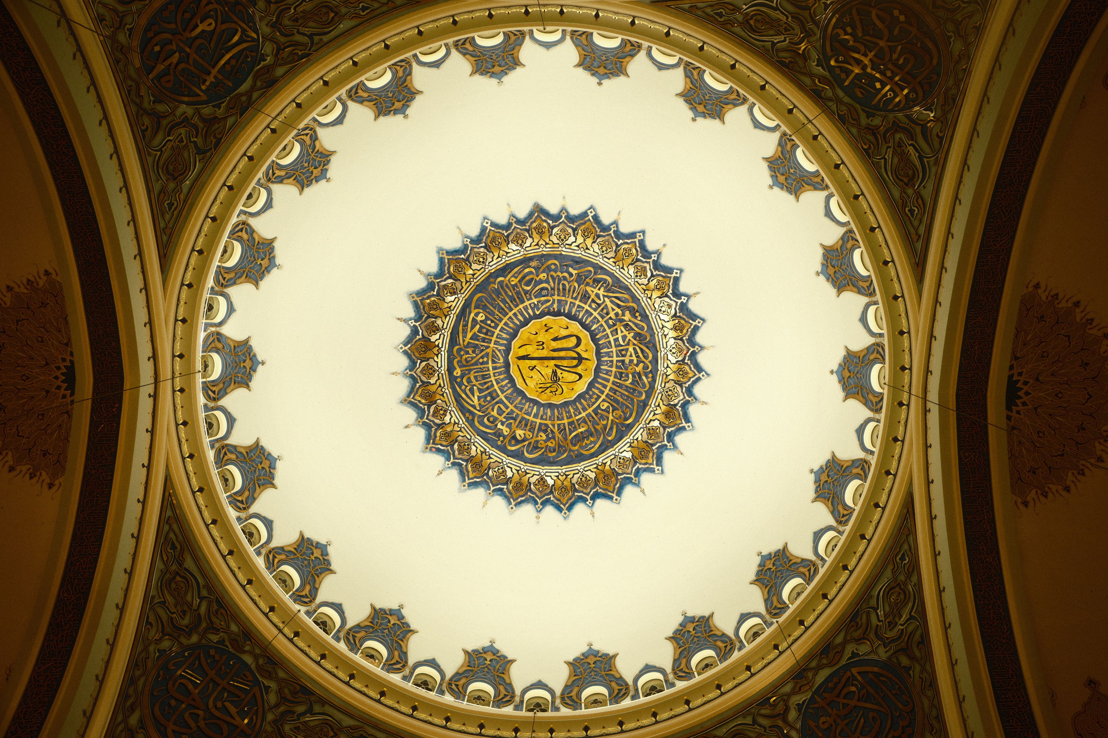 Ornate dome ceiling with Islamic calligraphy and intricate patterns in Istanbul mosque.