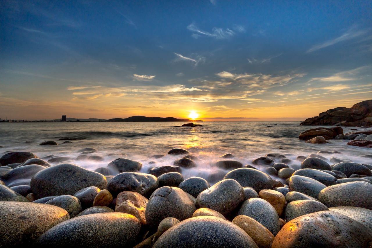 serene rocky shore landscape featuring a stunning sunset over the ocea