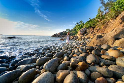 Photo Of Person Standing On Rocky Shore