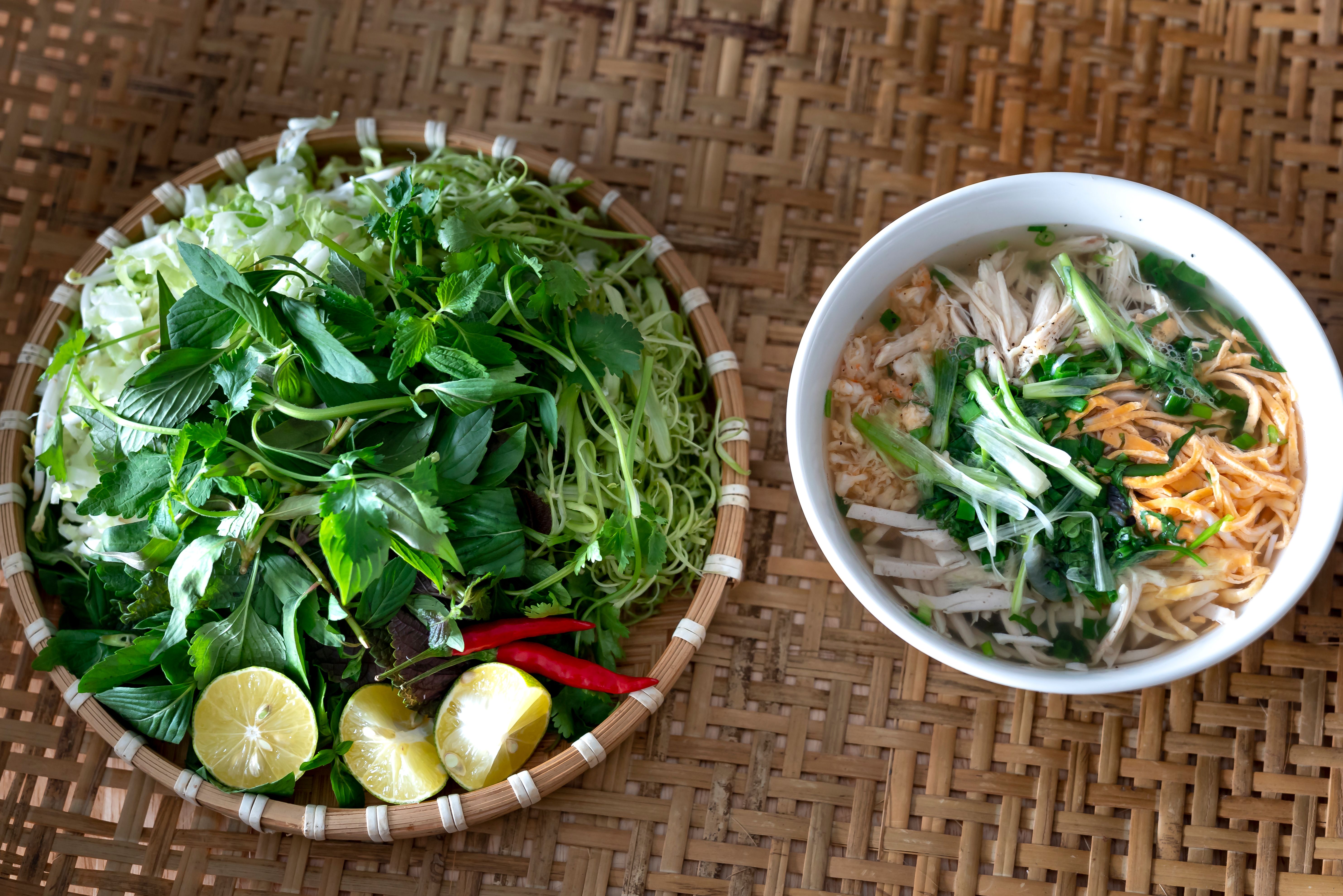 Delicious Vietnamese pho served with fresh herbs on a woven bamboo mat, capturing the essence of traditional cuisine.