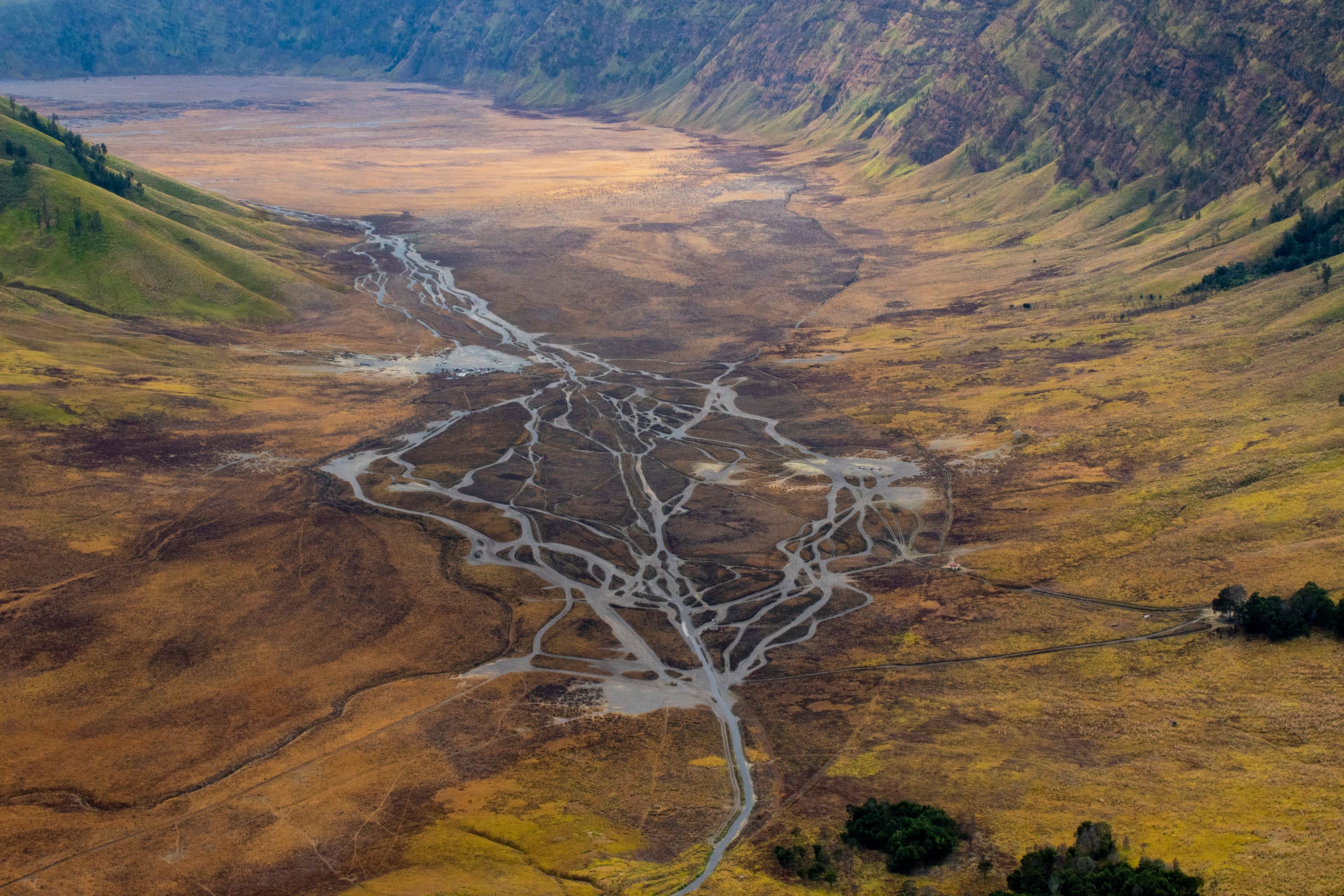 Indrukwekkende luchtfoto van de Bromo Vallei, die het droge landschap en de rivierstroken in Oost-Java toont.
