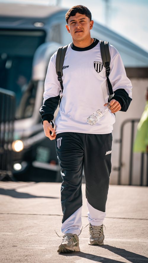 Free Young male athlete walks outdoors in team tracksuit, holding a water bottle. Bright, sunny day. Stock Photo