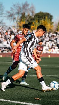 Dynamic action shot of soccer players competing during a match on a sunny day.