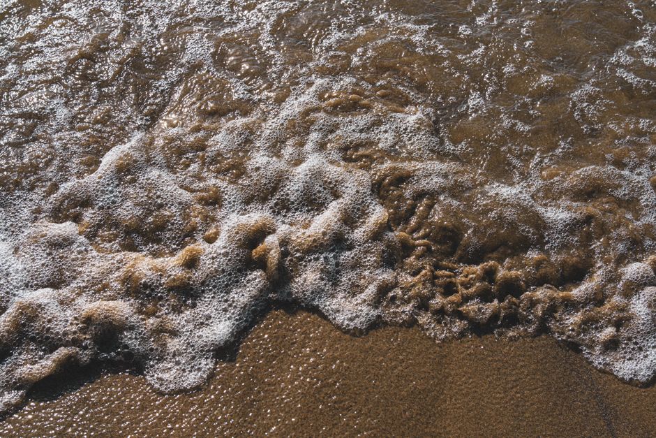 Gentle waves create foam patterns on a sandy beach in Da Nang, Vietnam.