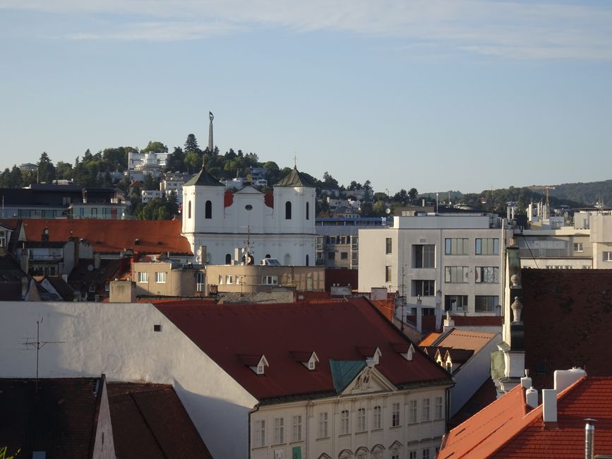A panoramic view of Bratislava featuring historic architecture and city rooftops under a clear blue sky.