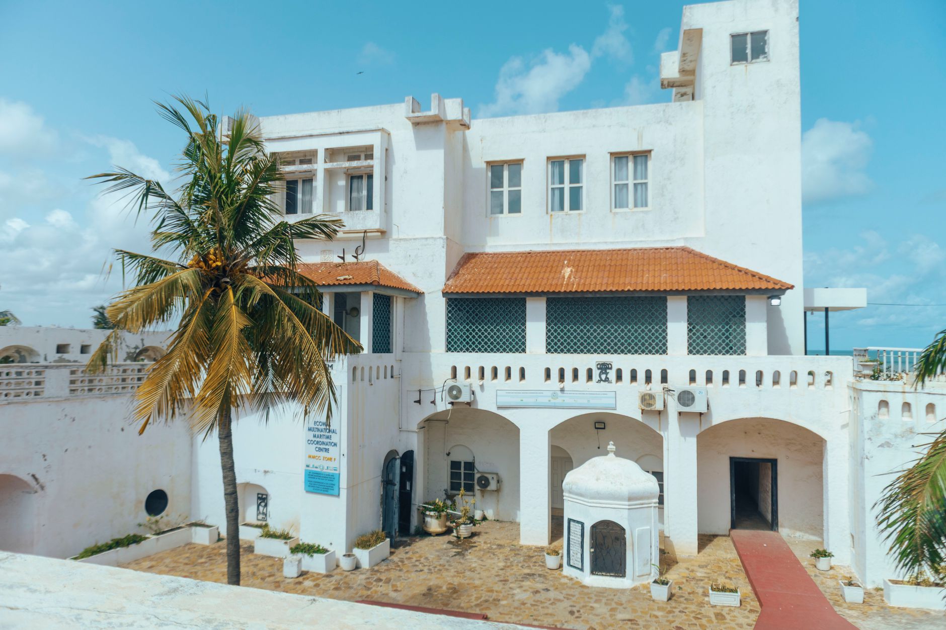 Magnifique vue d'un fort historique bordé de palmiers à Accra, illustrant l'architecture coloniale sous un ciel bleu.