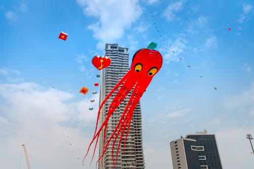 Colorful funny kites flying in sky in urban environment