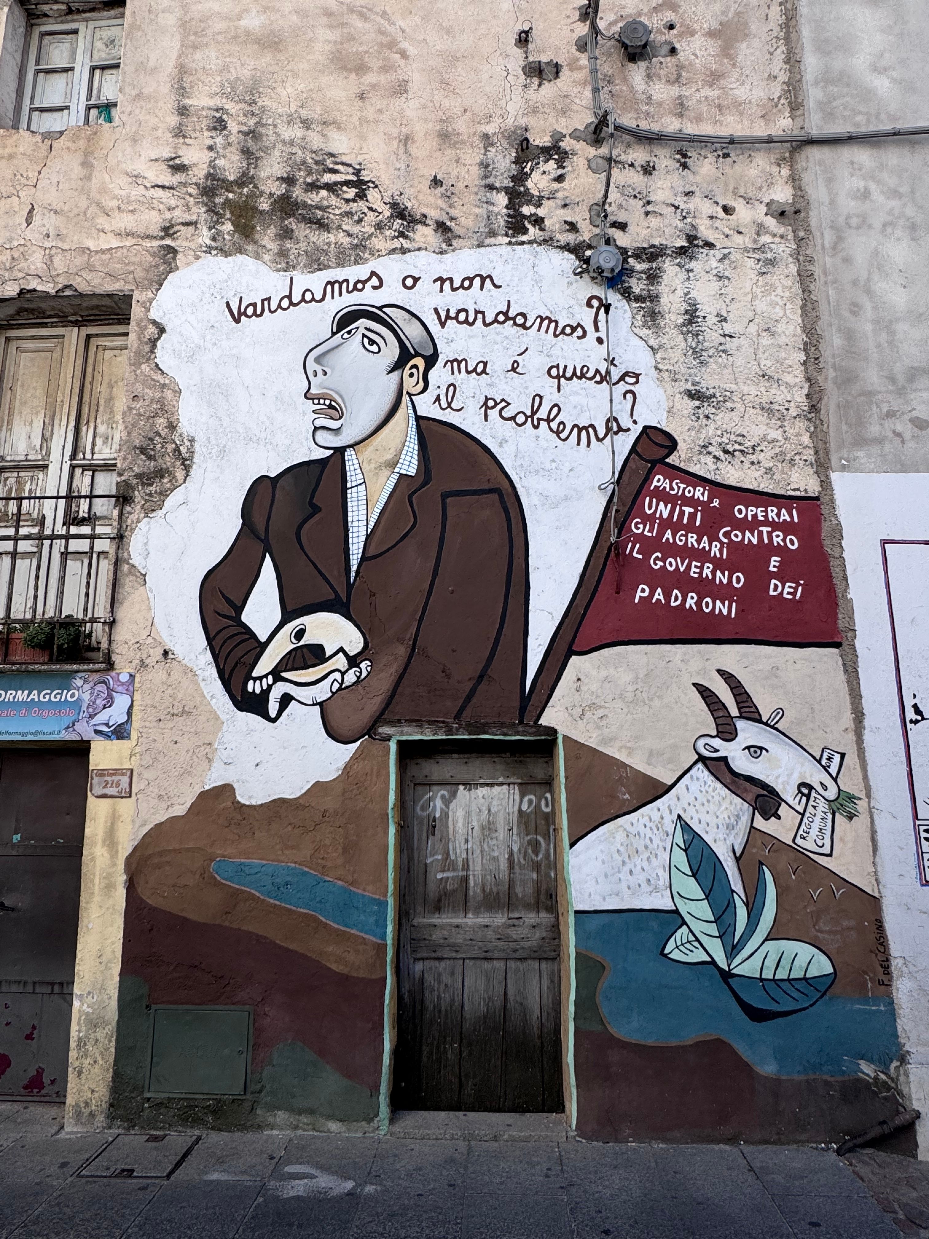Colorful street art mural on a building wall in Sardinia, Italy, highlighting social themes.