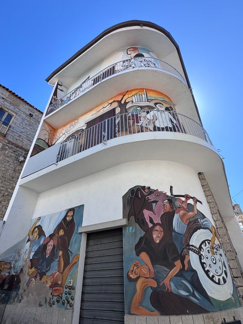 Free Colorful murals decorate a unique building facade in Sardinia, showcasing local art. Stock Photo