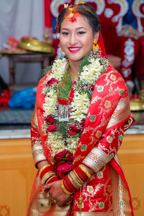 Free South Asian bride in vibrant traditional attire, adorned with floral garlands and gold jewelry. Stock Photo