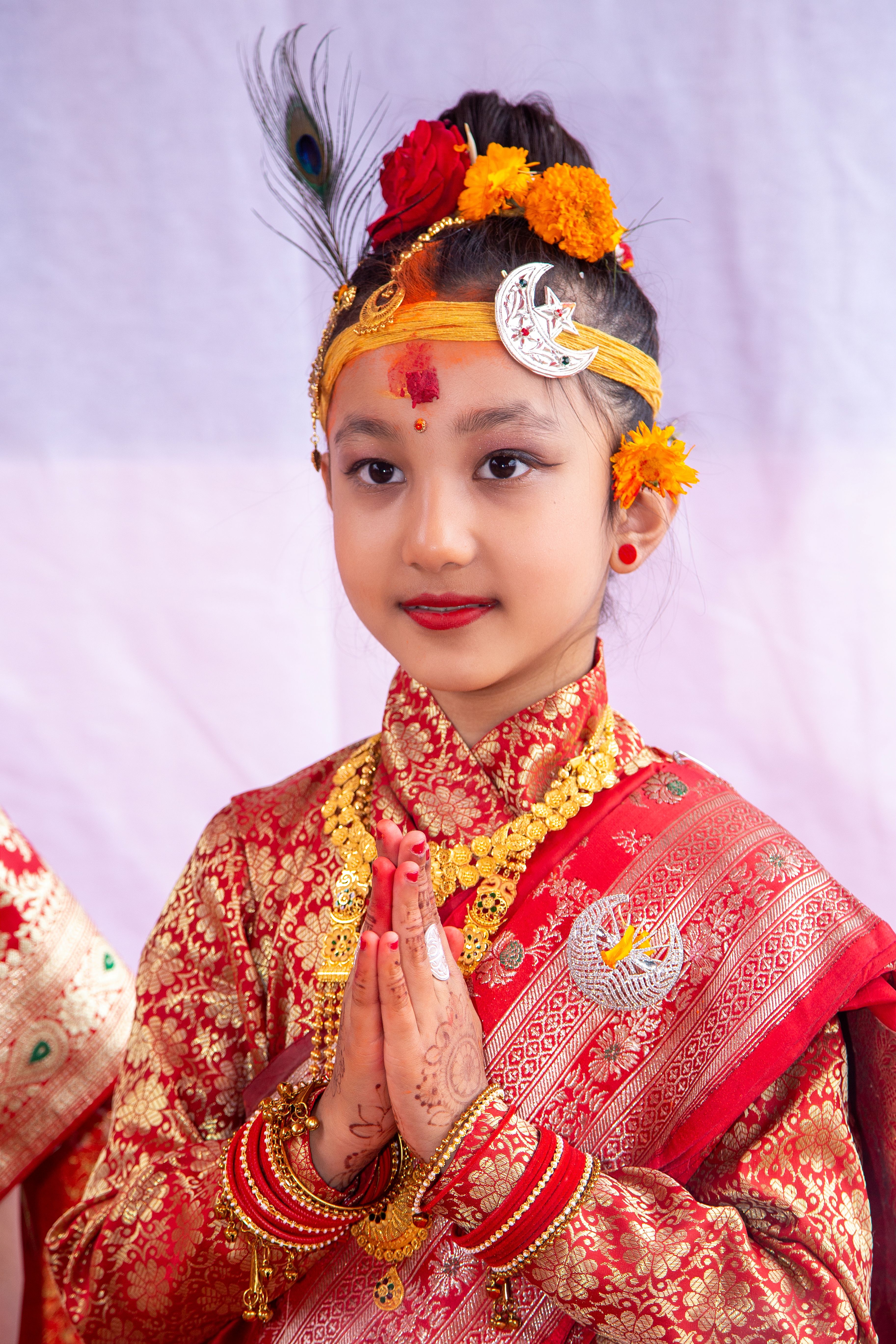 Young Nepali girl in vibrant traditional dress performing Namaste. Perfect for cultural and festive themes.
